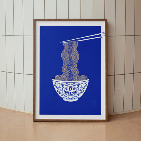 Framed artwork of a bowl with chopsticks on a blue background against a tiled wall.